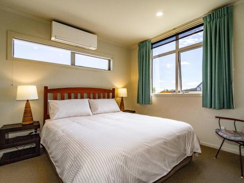 um quarto com uma grande cama branca e uma janela em Alpine Retreat - Ohakune Holiday Home em Ohakune