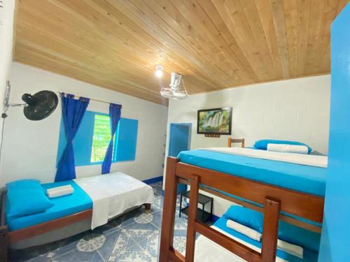 een slaapkamer met 2 bedden en blauwe stoelen bij HOSTAL EL DESCANSO in Capurganá