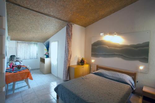 Un dormitorio con una cama y una mesa con un niño. en Residence San Damiano - Location Appartements, Studios & Chambres, en Algajola