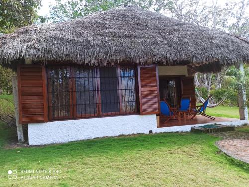 a small hut with a thatched roof and two chairs at Hosteria Cumilinche in Same