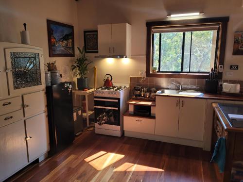 a kitchen with white cabinets and a black refrigerator at Kookaburra Cottage at Uralba Eco Cottages in Upper Horseshoe Creek