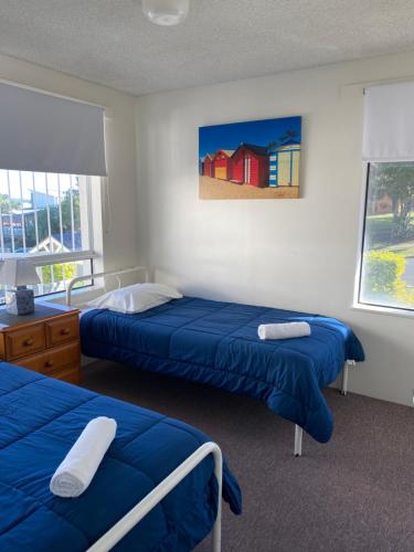 a bedroom with two beds and a painting on the wall at Bayview Harbourview Apartments in Mooloolaba
