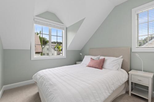 a white bedroom with a bed and two windows at Sandy Jandal - 3-5 Bedroom - Russell Cottages in Russell