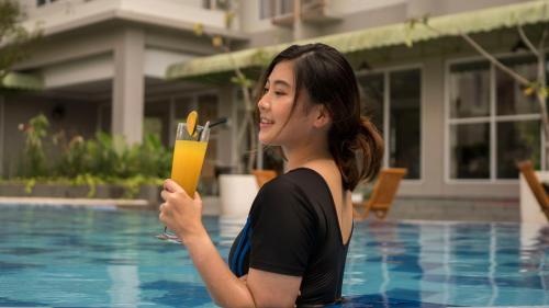 a woman standing next to a pool holding a drink at Patra Dumai Hotel in Dumai