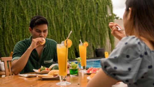 a man and woman sitting at a table eating food at Patra Dumai Hotel in Dumai
