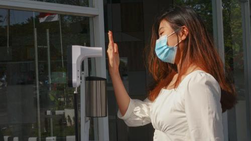 a woman wearing a face mask in front of a window at Patra Dumai Hotel in Dumai