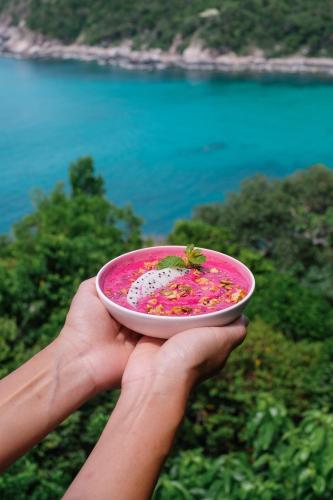 a person holding a pink plate with a insect on it at Baan Talay Resort & Yoga in Koh Tao