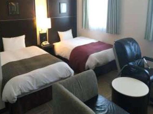 une chambre d'hôtel avec deux lits et un canapé dans l'établissement Ariston Inn Kanda Kitakyusyu Airport, à Kanda