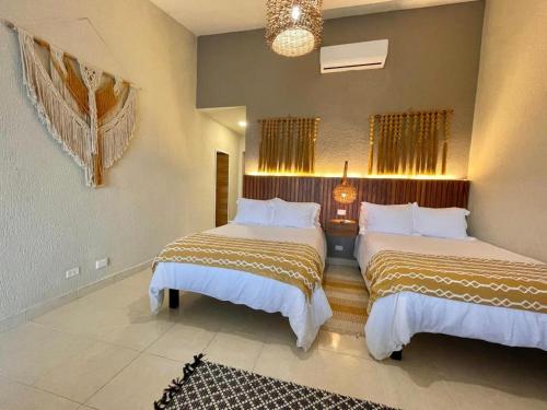 a bedroom with two beds and a chandelier at All Ritmo by Andiani Travel in Cancún
