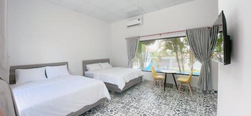 a bedroom with two beds and a table and a window at Bao Dien Guesthouse in Bao Loc
