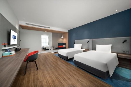 a hotel room with two beds and a chair at Holiday Inn Express Zhuhai Gongbei by IHG in Zhuhai