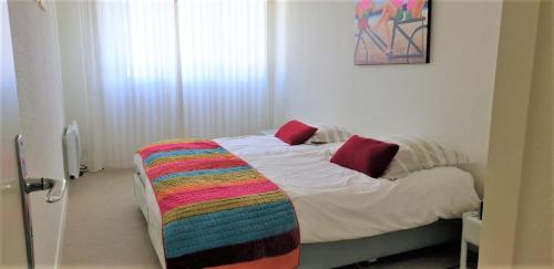 - une chambre avec un lit et une couverture colorée dans l'établissement Le Calypso, à Les Sables-dʼOlonne