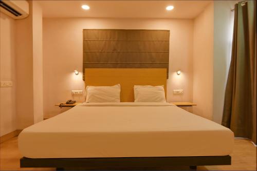 a bedroom with a large white bed with a headboard at FabHotel Suncitel Dum Dum Airport in Gauripur