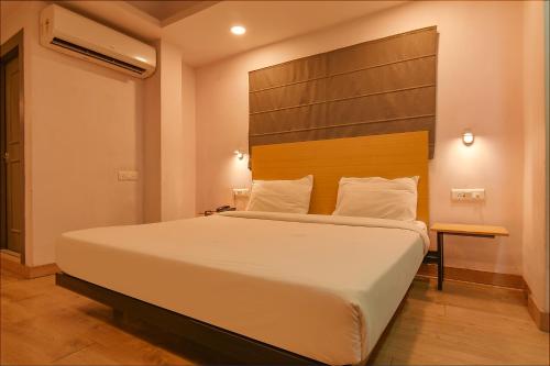 a bedroom with a large bed with a wooden headboard at FabHotel Suncitel Dum Dum Airport in Gauripur