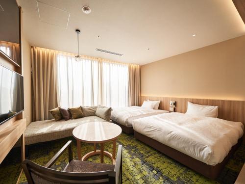 a hotel room with two beds and a couch at WeBase TAKAMATSU in Takamatsu