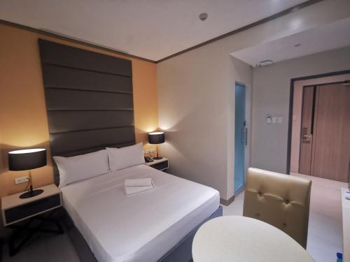 a bedroom with a large white bed and a chair at Yes Hotel Pandi Bulacan in Pandi