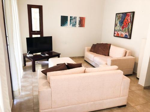 uma sala de estar com dois sofás e uma televisão em Triplex vista mar no Pipa Beleza em Pipa