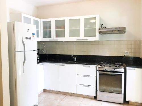 a kitchen with white cabinets and a stove and a refrigerator at Triplex vista mar no Pipa Beleza in Pipa