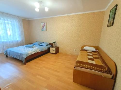 um quarto com uma cama e piso em madeira em 1 комнатные апартаменты на Ауэльбекова 138 em Kokshetau