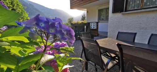 a balcony with a table and purple flowers at Haus Tisch in Schruns-Tschagguns