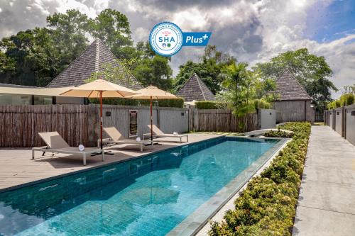 a swimming pool with chairs and umbrellas next to a house at Tao Resort and Villas (SHA Extra+) in Phuket
