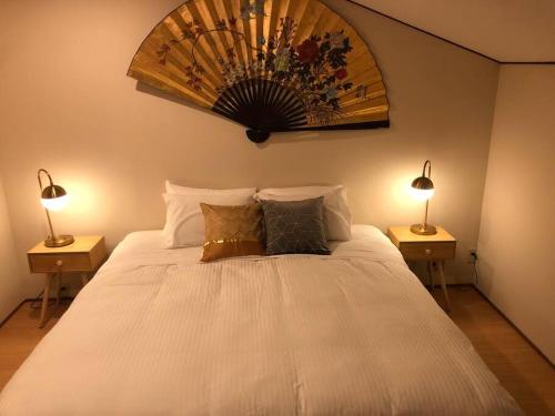 a bedroom with a large white bed with two lamps at Riders Ridge Luxury Chalet sleeps 12 Ski In Ski Out Myoko in Akakura