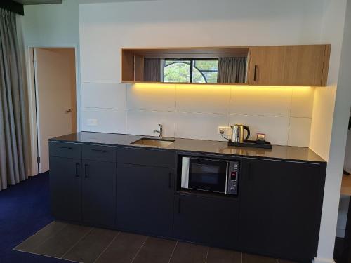 a kitchen with a sink and a microwave at Nesuto Curtin Perth Hotel in Perth