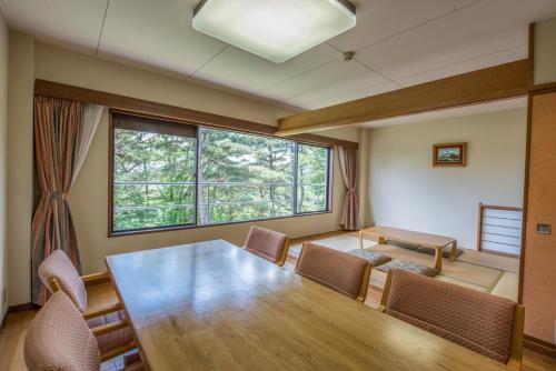 伊豆市にあるホテルラフォーレ修善寺のテーブルと椅子、大きな窓が備わる客室です。
