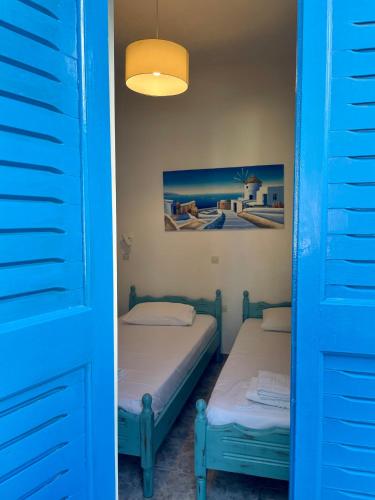 a pair of beds in a room with blue doors at Anna Maria Rooms Santorini in Perissa