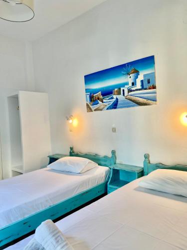 two beds in a room with a picture on the wall at Anna Maria Rooms Santorini in Perissa