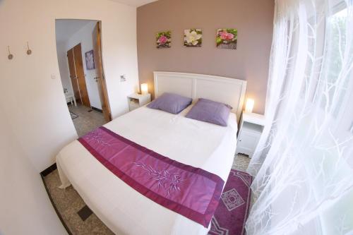 a bedroom with a large white bed with purple sheets at La Maison D'Adam in Hellemmes-Lille