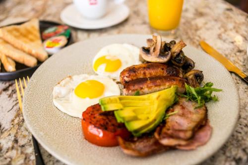 einen Teller mit Lebensmitteln mit Eiern, Fleisch und Gemüse in der Unterkunft Emakhosini Boutique Hotel in Durban