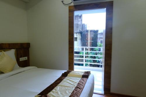 a bedroom with a bed and a large window at Hotel Girija Sunrise 300 Meter from Baba Dham Temple in Deoghar