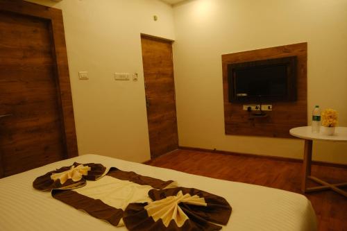 a bedroom with a bed with a television on the wall at Hotel Girija Sunrise 300 Meter from Baba Dham Temple in Deoghar