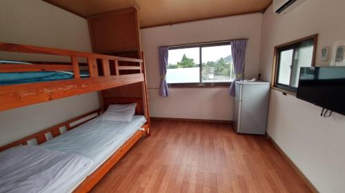 a bedroom with two bunk beds and a refrigerator at Kerama Backpackers in Tokashiki