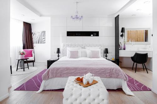 a white bedroom with a large bed and a table at EXCLUSIVE EuApartments in Grodno