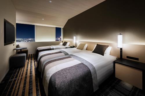 a hotel room with two beds and a television at Hotel Hankyu RESPIRE OSAKA in Osaka