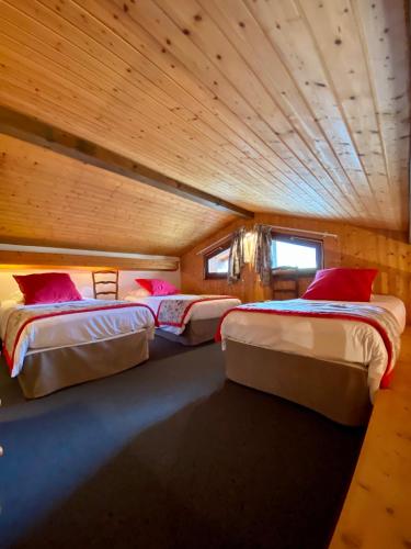 two beds in a room with a wooden ceiling at Hotel Les Bruyères in Morzine