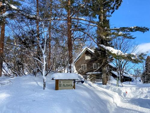 a sign in the snow in front of a house at Pension Razteca in Hakuba