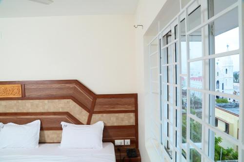 a bedroom with a bed and a large window at Annai in Saravana Bhavan Fine stay and Restaurant in Velānganni