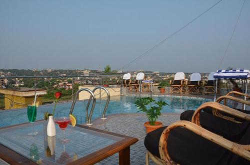 un patio con mesa, sillas y piscina en Boshan Hotels, en Mapusa