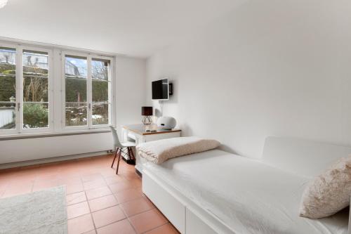 a white bedroom with a bed and a window at Cozy Boutique Apartment at Mt. Rigi in Goldau