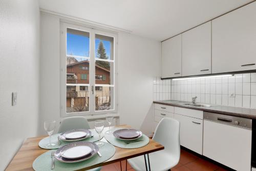 a kitchen with a table and chairs and a kitchen with white cabinets at Cozy Boutique Apartment at Mt. Rigi in Goldau