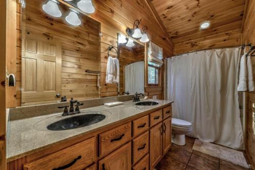a log cabin bathroom with two sinks and a toilet at Love You Deerly in Morganton