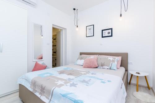 a white bedroom with a bed with pink pillows at Apartments Bell Memories in Cavtat
