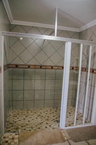 a shower with glass doors in a room at Towers Lodge in Boksburg