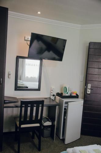 a desk with a mirror and a chair in a room at Towers Lodge in Boksburg