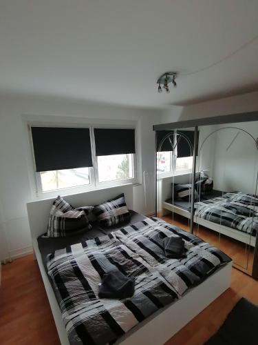 a bedroom with a large bed and two windows at schöne Ferienwohnung über den Dächern von Plauen in Plauen