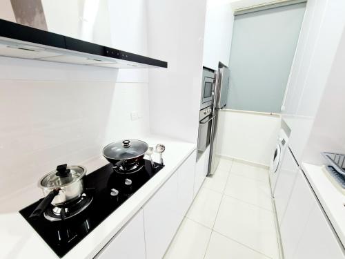 a white kitchen with two pots and pans on a stove at Beacon Executive Suites in George Town