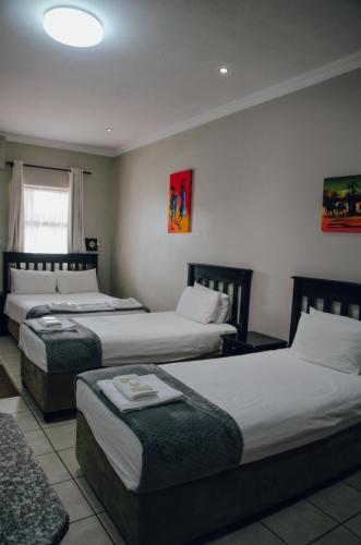 a hotel room with three beds and a window at Towers Lodge in Boksburg